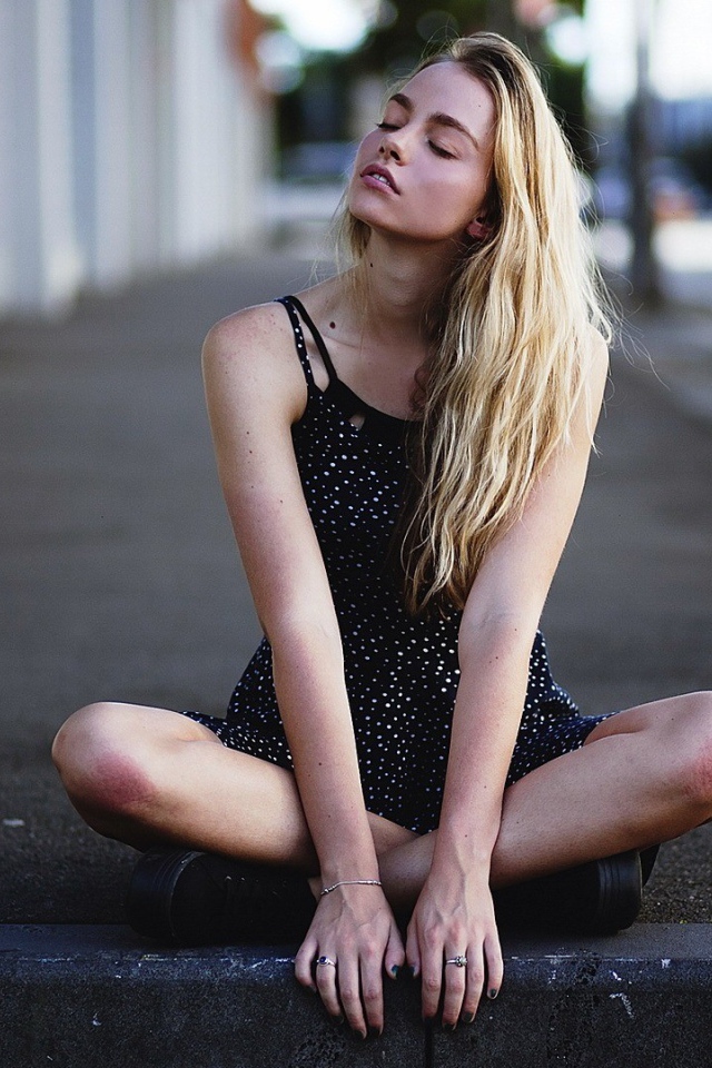 Блондинка медитирует на асфальте