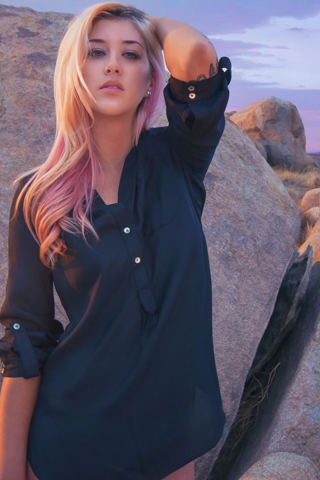 Блондинка стоит у большого валуна