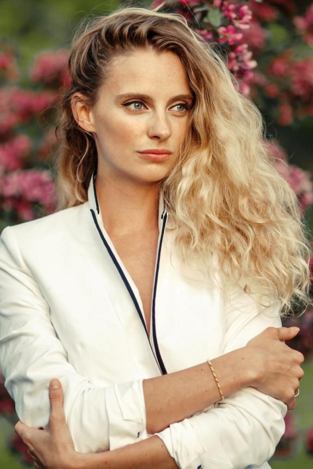 Голубоглазая блондинка на фоне цветущих деревьев