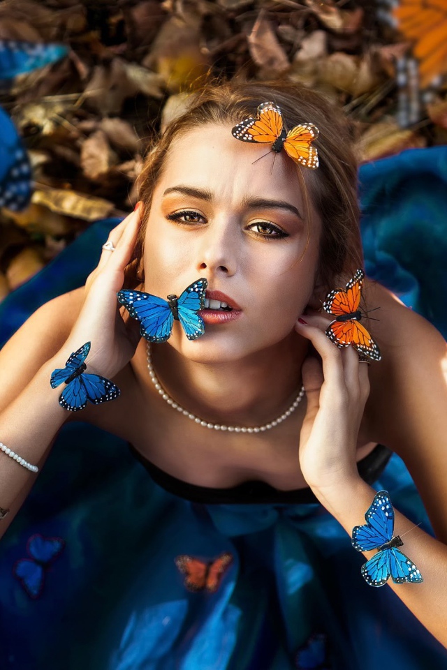 Голубые и оранжевые бабочки на девушке