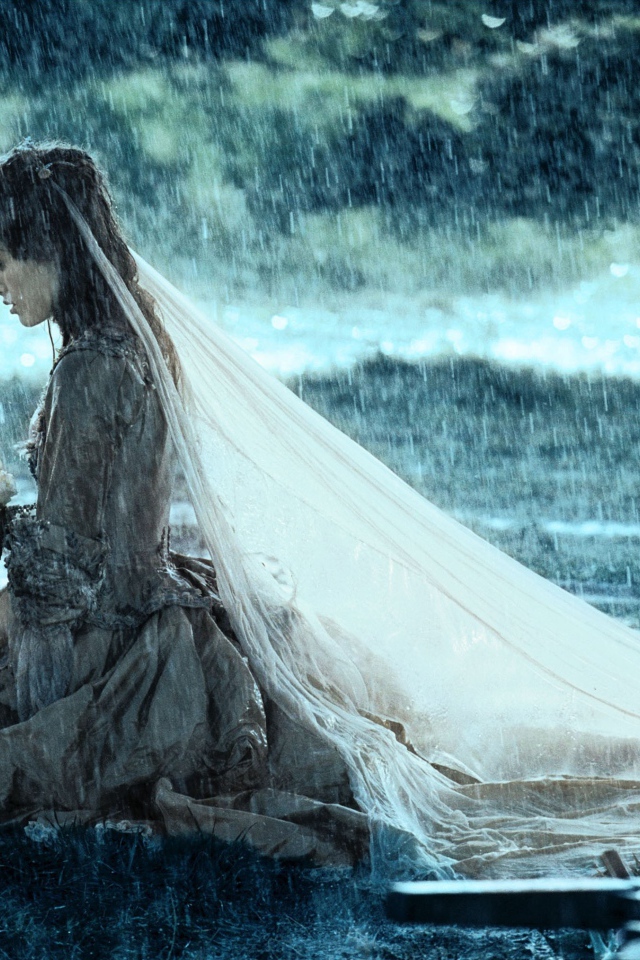 Невеста сидит на коленях под дождем