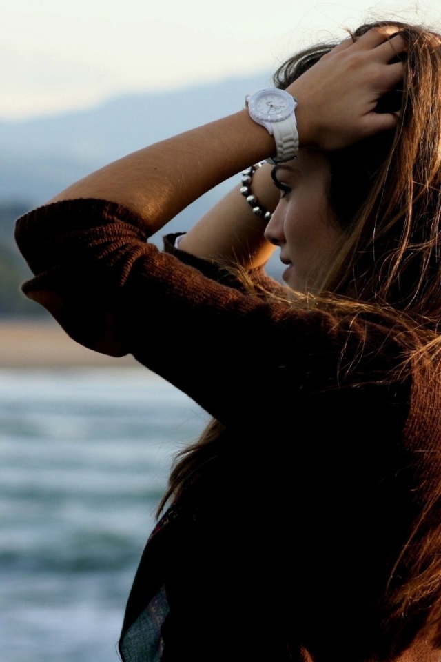 Шатенка с длинными волосами поправляет прическу