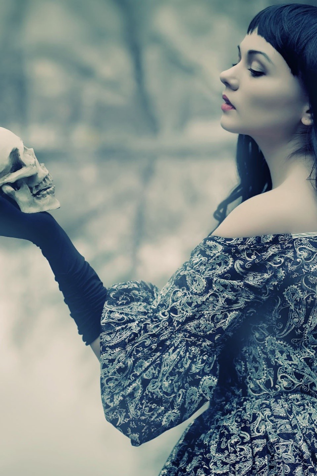 Брюнетка держит в руке череп