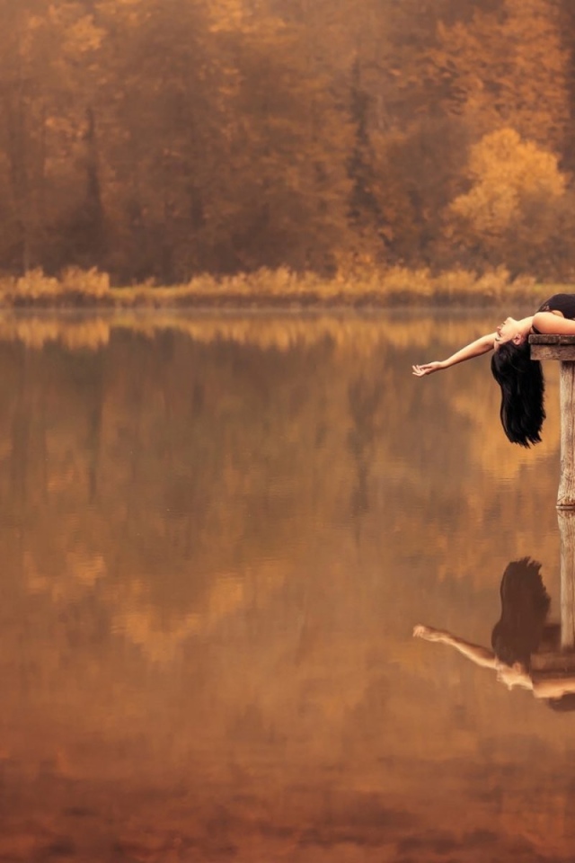 Брюнетка лежит на пирсе на озере