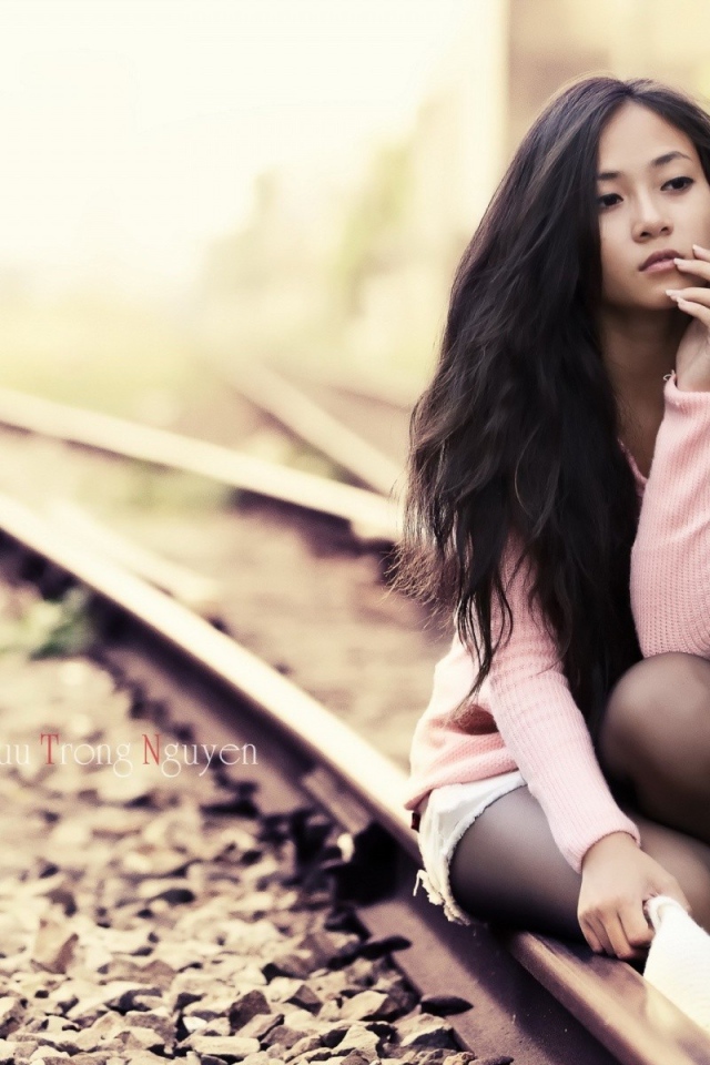 Брюнетка сидит на холодных рельсах