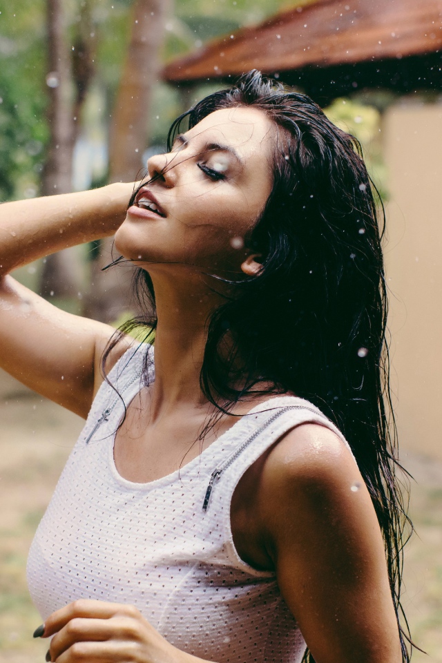 Брюнетка подставляет лицо под капли дождя