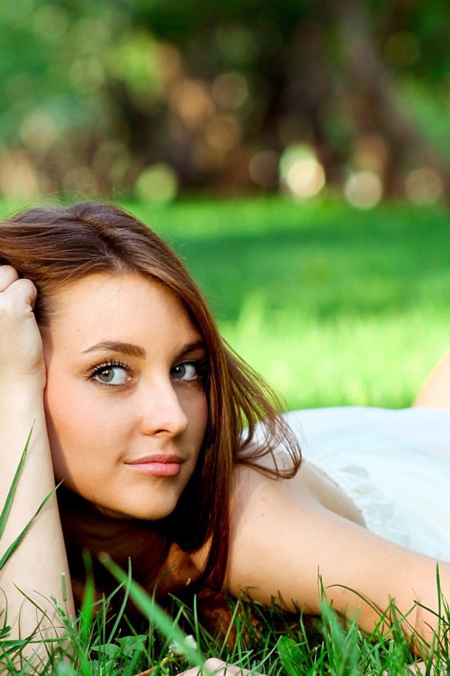 Беззаботная девушка лежит на зеленой траве