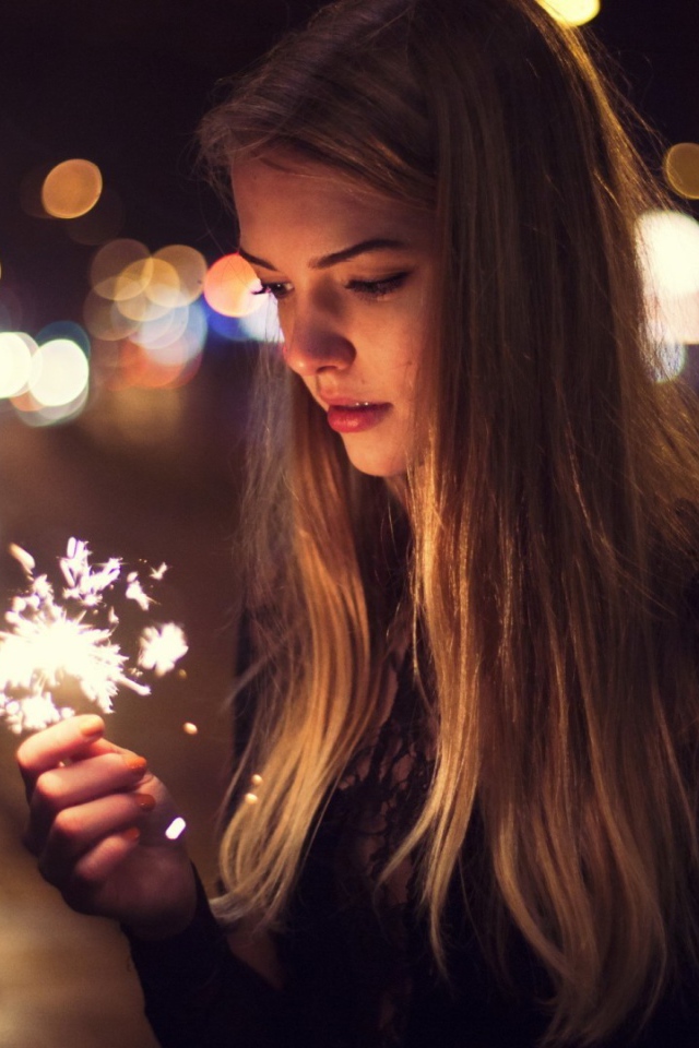 Девушка держит в руке бенгальский огонь