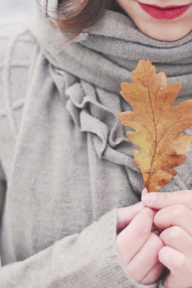 Девушка держит в руках желтый лист