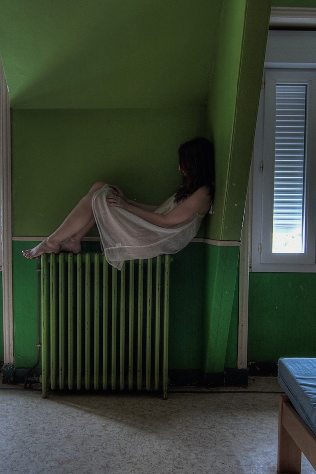 Девушка в ночной рубашке сидит на батарее