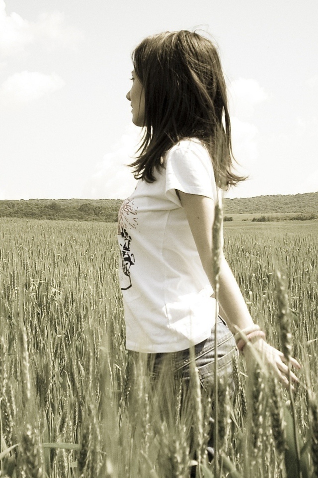 Девушка в белой футболке гуляет по пшеничному полю