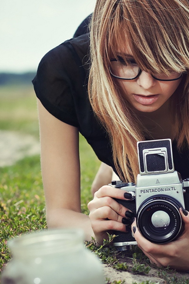 Девушка в очках фотографирует траву