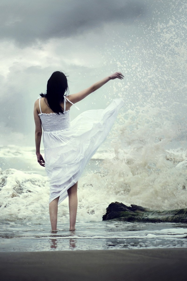 Девушка в белом платье среди брызг прибоя