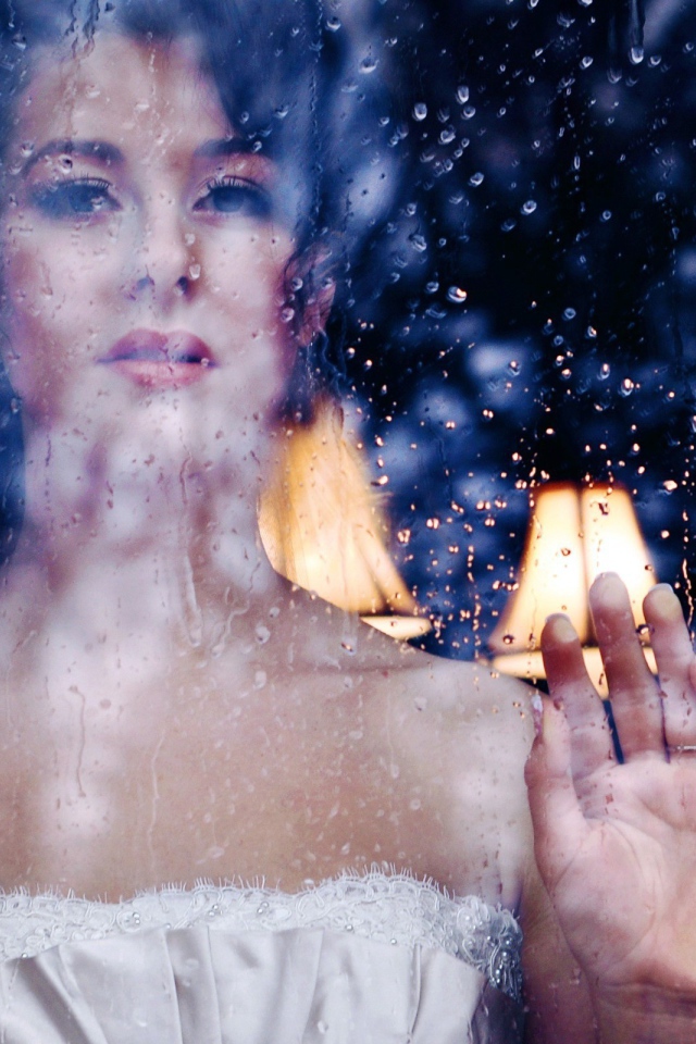 Девушка в белом платье за мокрым стеклом