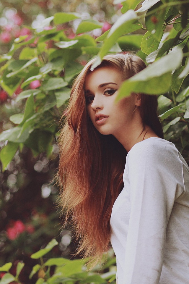 Девушка в белом платье гуляет в саду