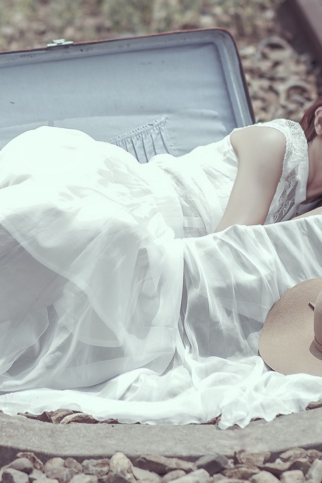 Девушка лежит в чемодане на рельсах