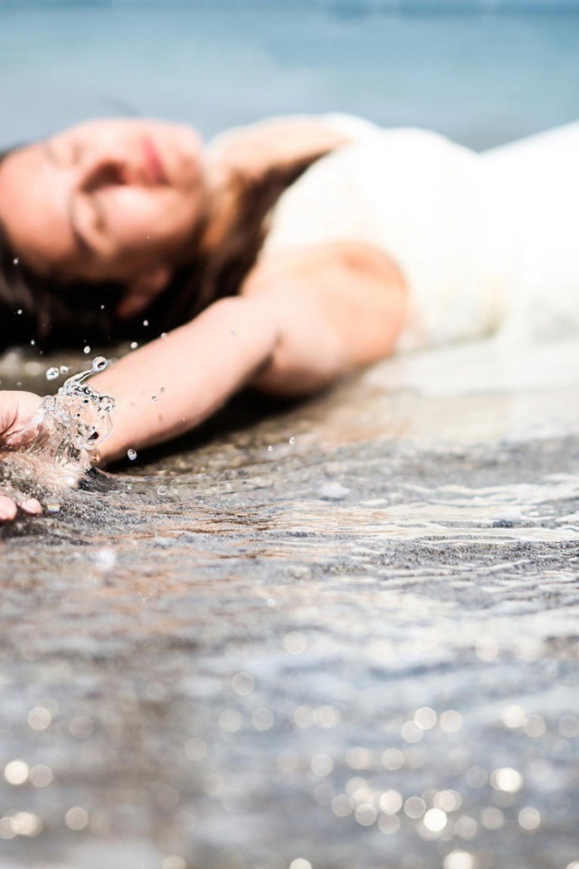 Девушка лежит в волне прибоя