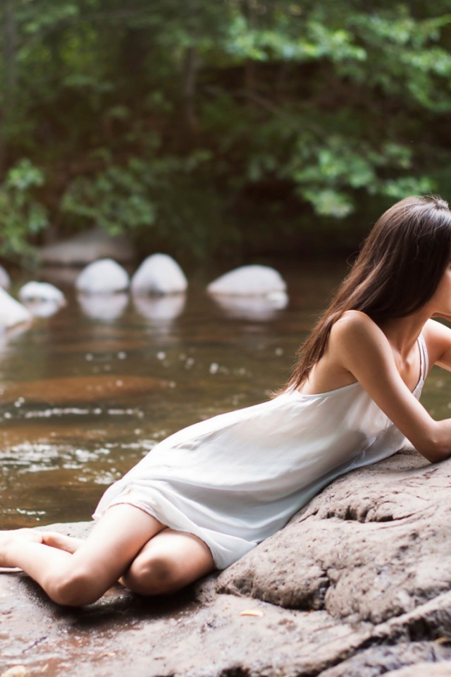 Девушка лежит на камне у реки