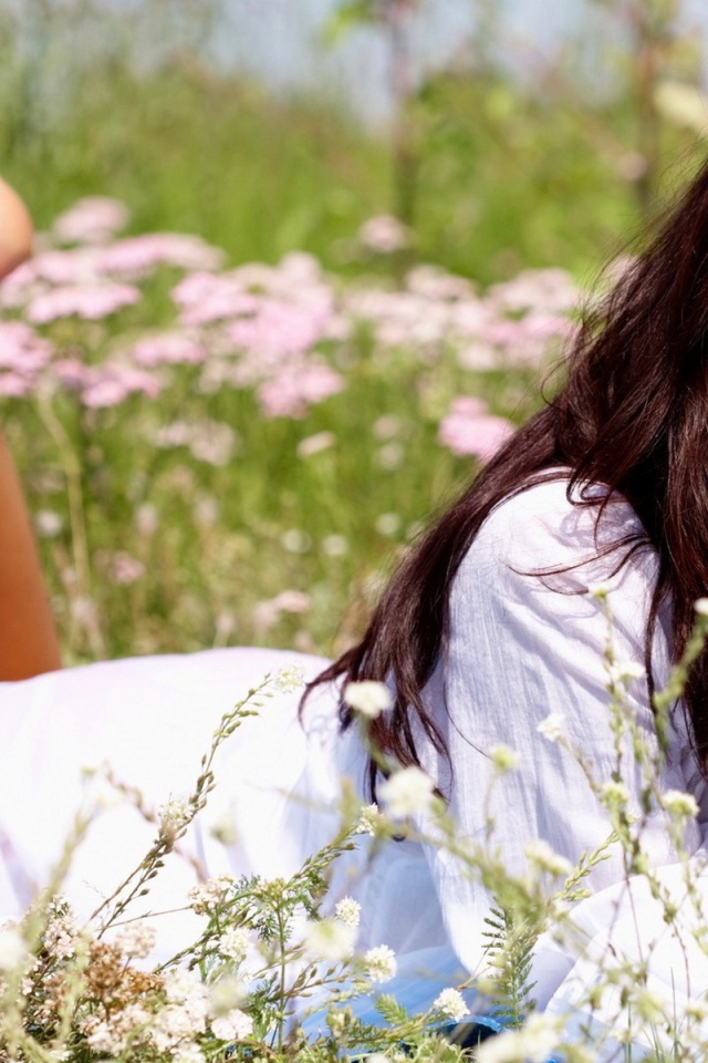 Девушка лежит на животе и держит в руке белый цветок