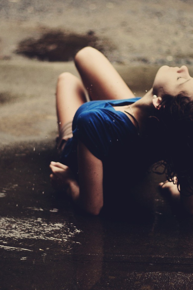 Девушка лежит на асфальте под дождем