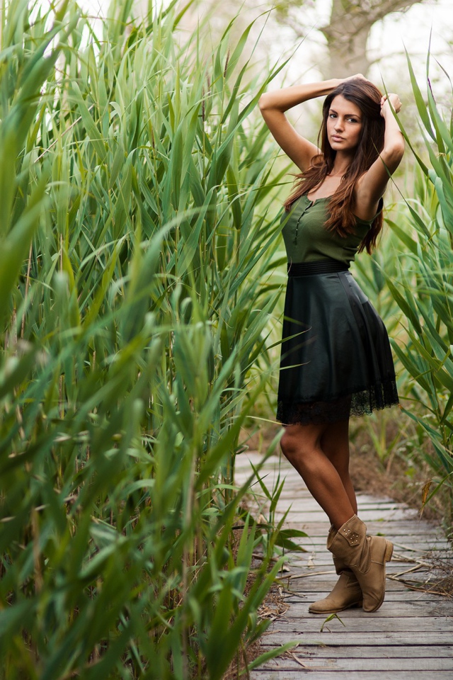 Девушка на деревянной дорожке среди камышей