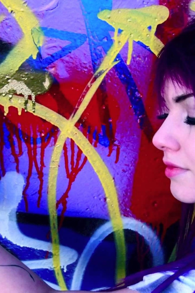 Девушка рисует граффити на стене