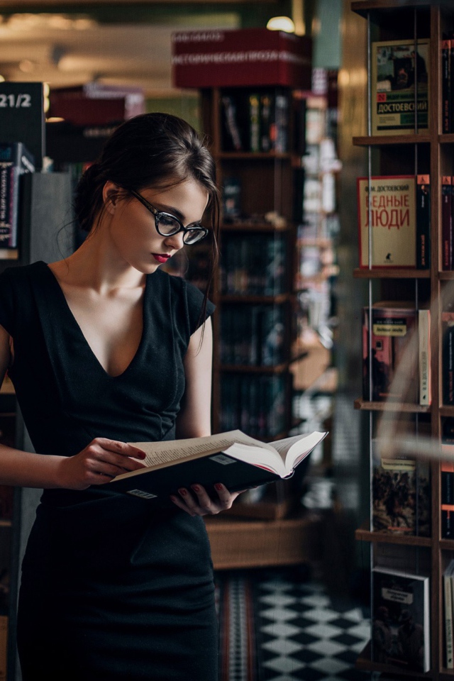 Девушка читает среди книжных полок