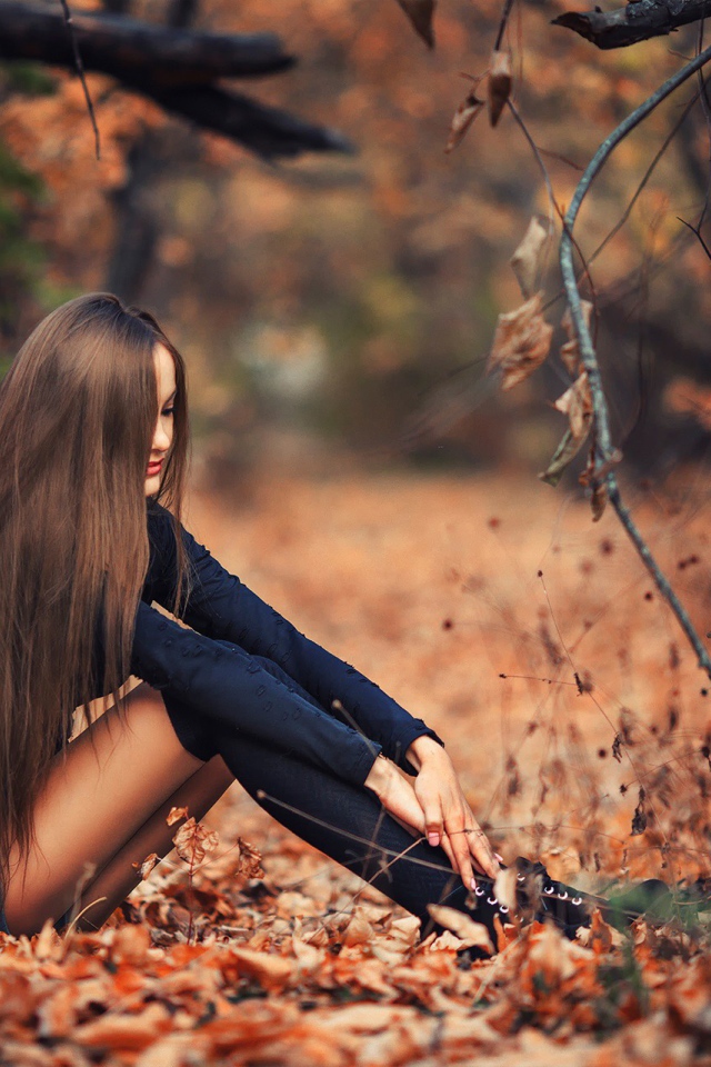 Девушка сидит на осенней листве