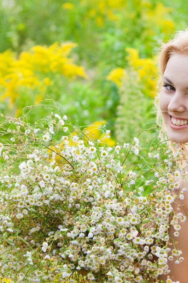 Девушка улыбается, держа в руках букет ромашек