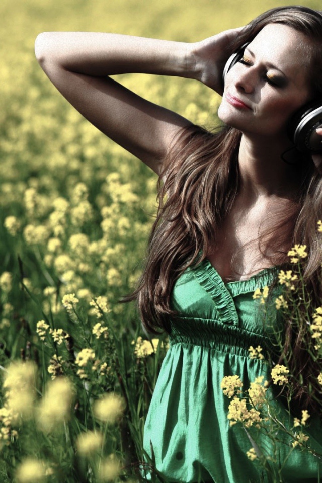 Девушка стоит среди цветов в наушниках