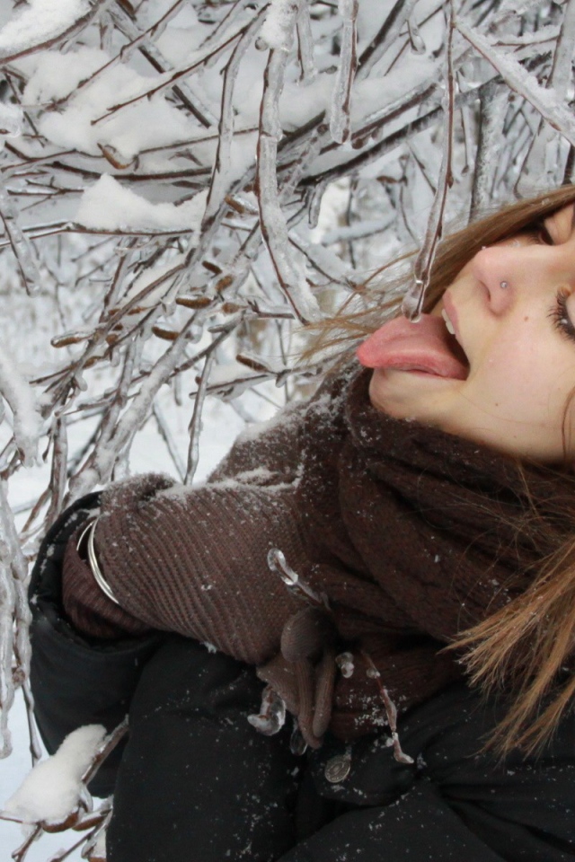 Девушка пробует сосульку на вкус