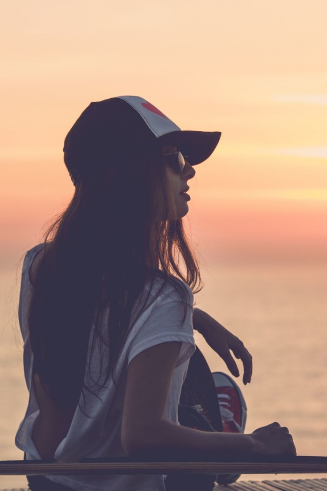 Девушка смотрит на закат на пляже