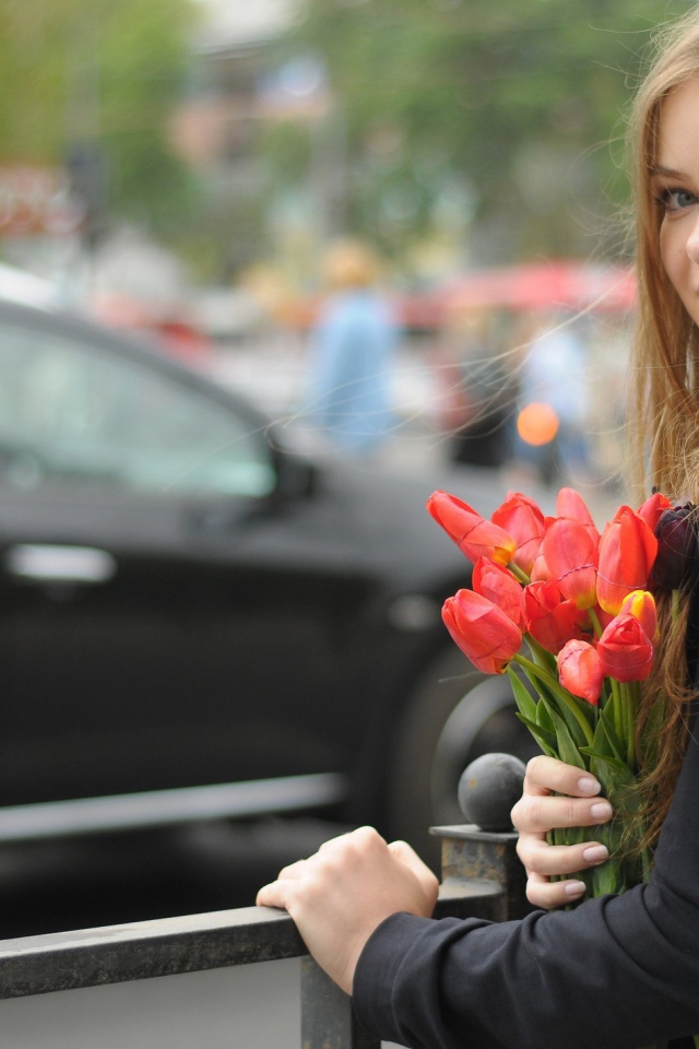 Девушка с букетом тюльпанов стоит у забора