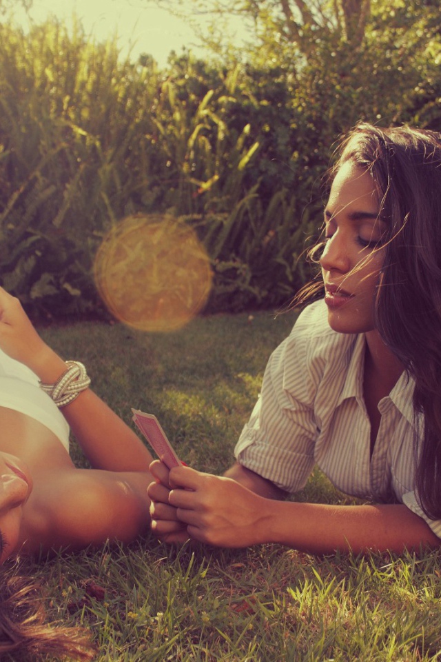 Девушки играют в карты на газоне