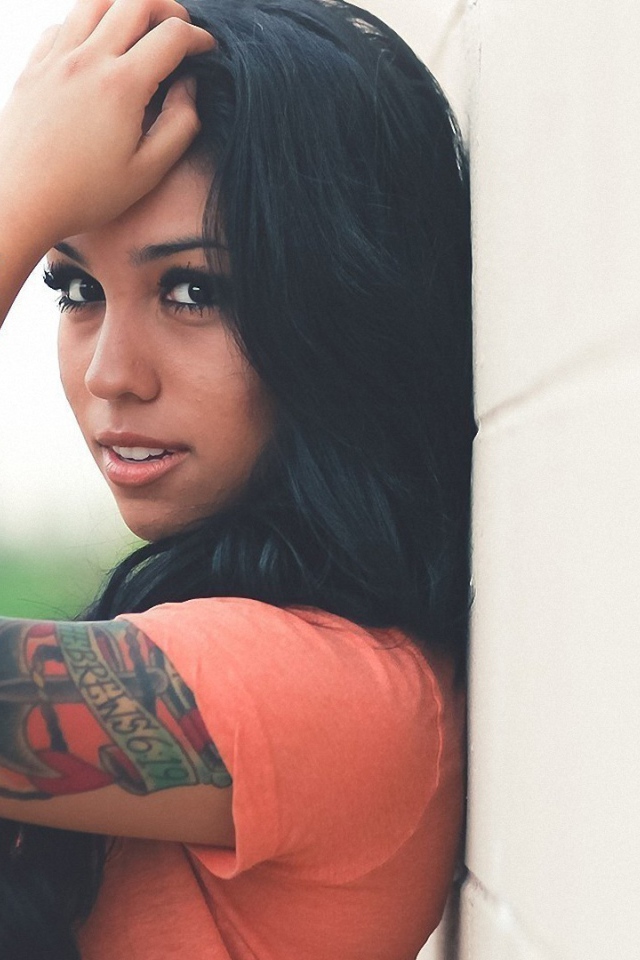 Страстная длинноволосая брюнетка прислонилась к стене