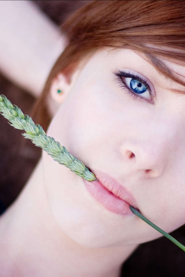 Зеленый колосок во рту у девушки