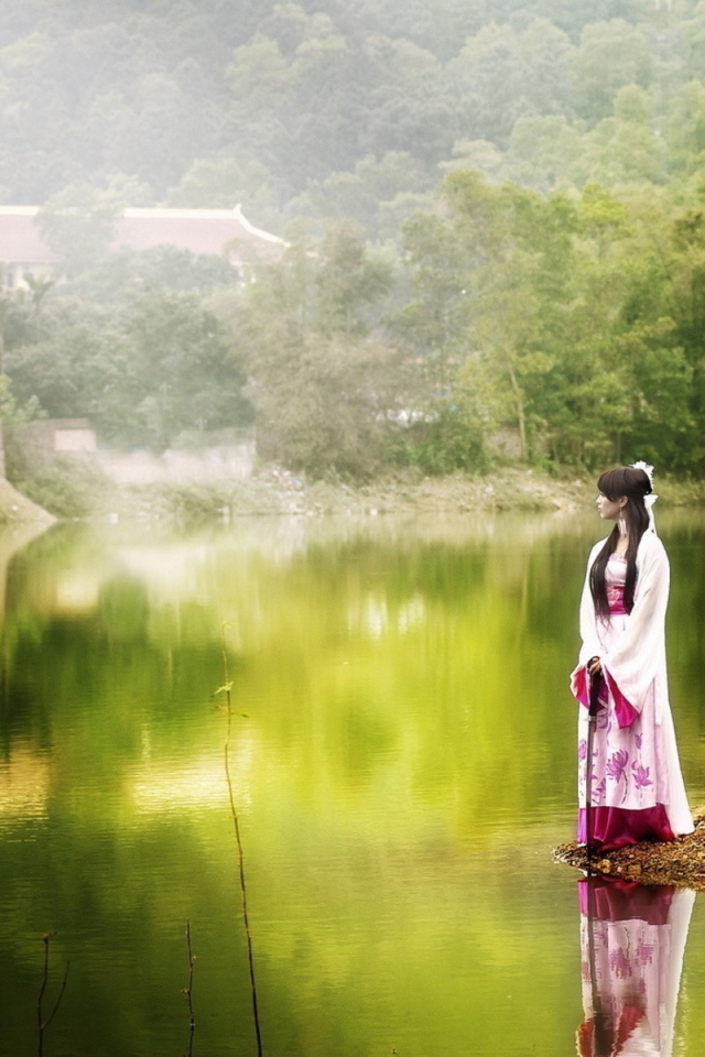 Японская девушка стоит на берегу водоема