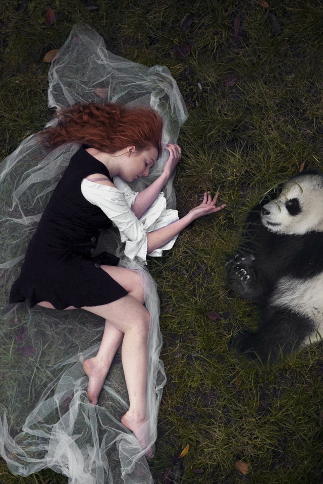 Девушка и панда лежат рядом на траве