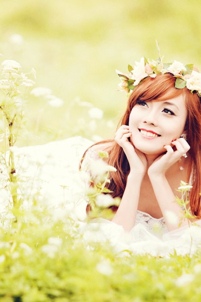 Рыжая японская девушка лежит в поле цветов