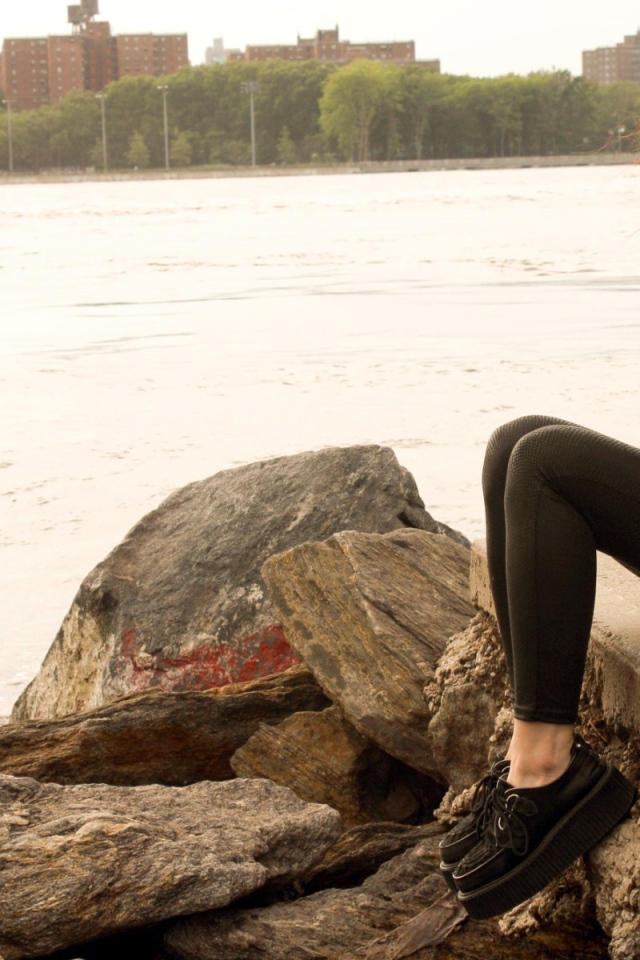 Рыжая девушка сидит на плитах набережной