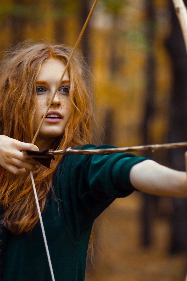 Рыжая девушка целится из лука