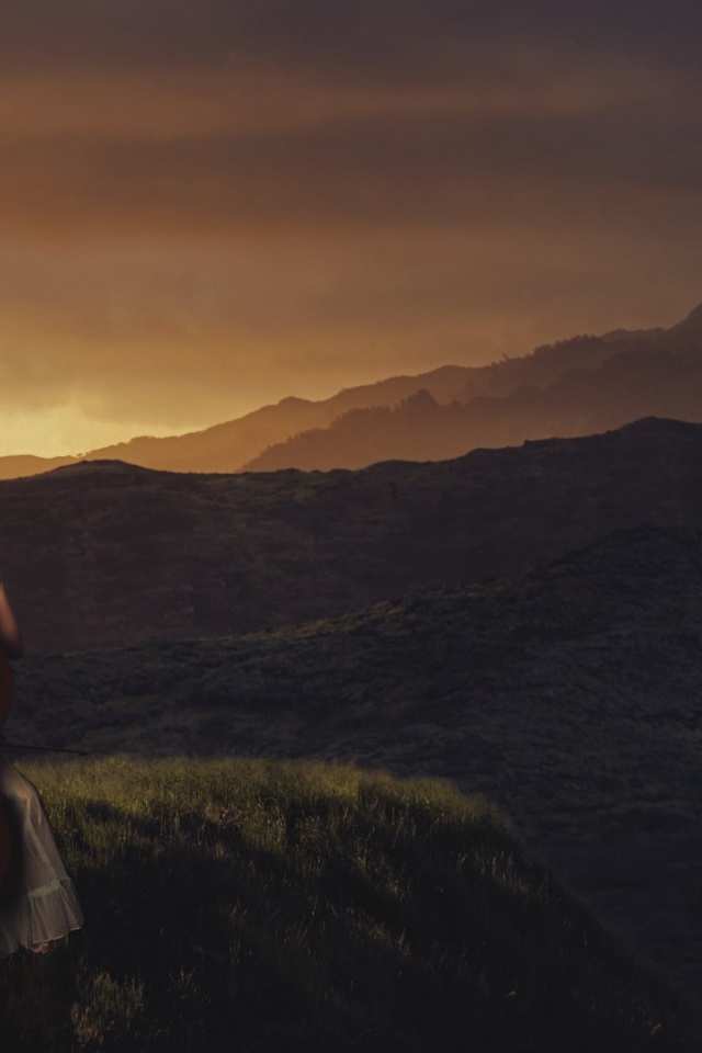 Девушка играет на виолончели на фоне гор