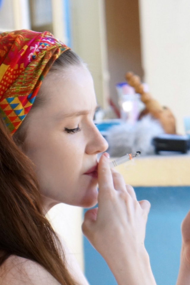 Девушка курит и смотрит на экран телефона