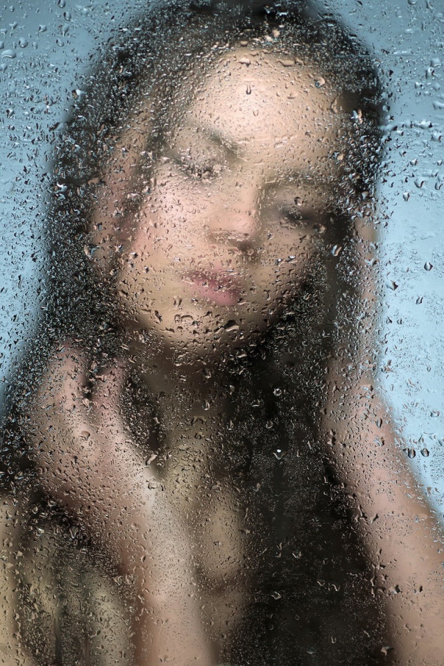 Девушка позади мокрого стекла