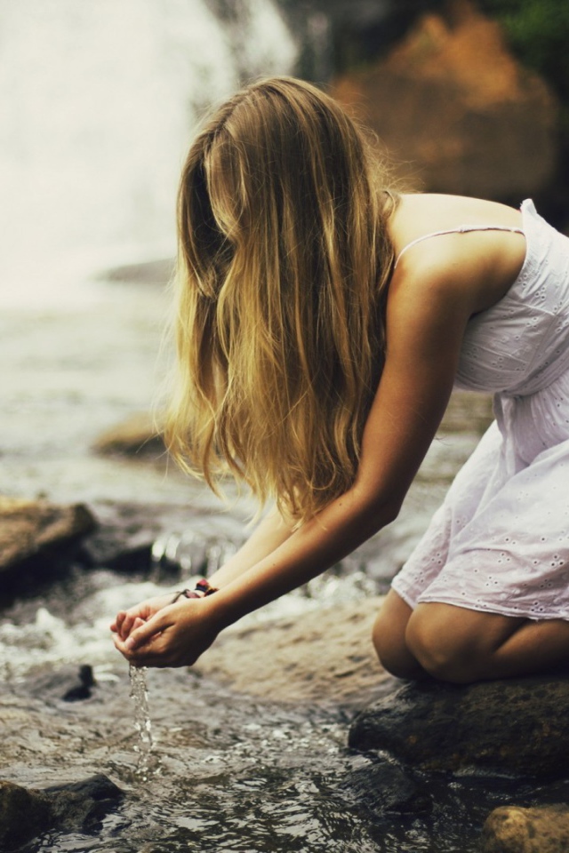 Девушка черпает воду из ручья