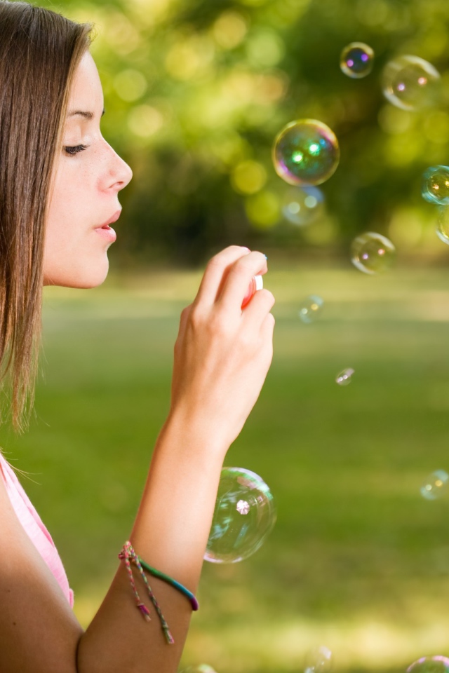 Девушка в розовой футболке запускает мыльные пузыри