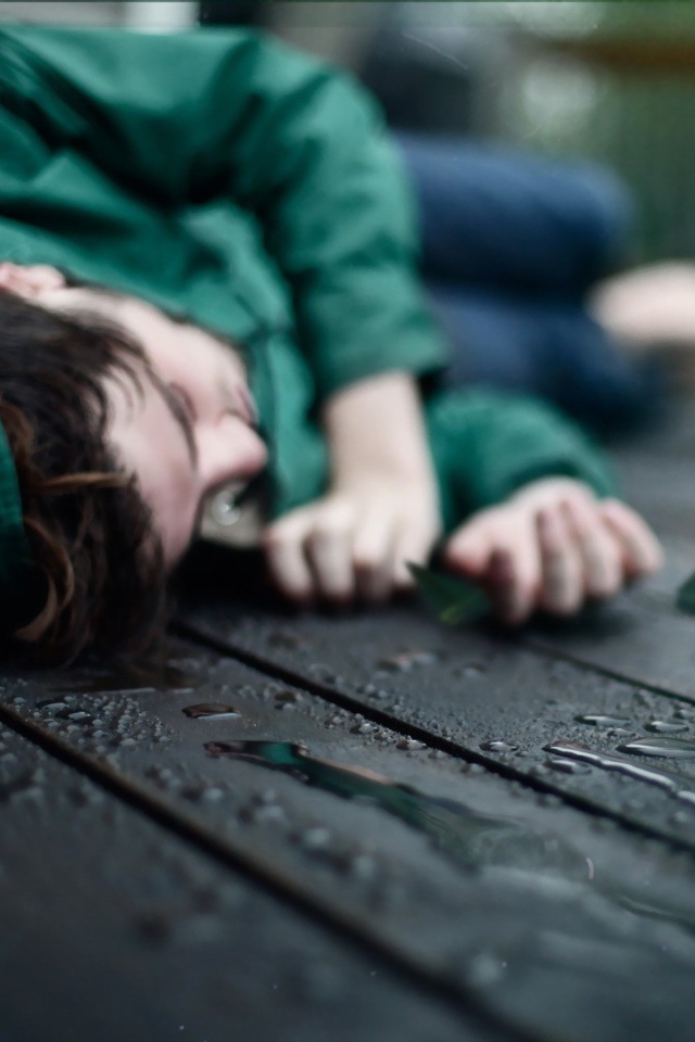 Девушка в зеленом лежит на мокрых досках