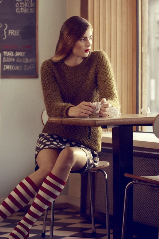 Девушка в полосатых чулках смотрит в окно