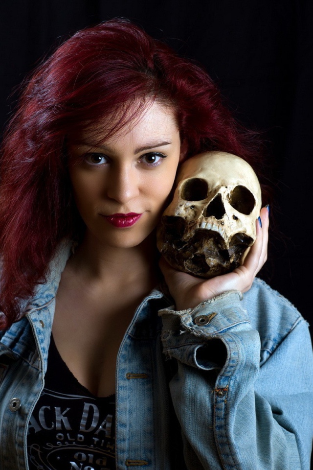 Девушка в джинсовой куртке держит череп на плече