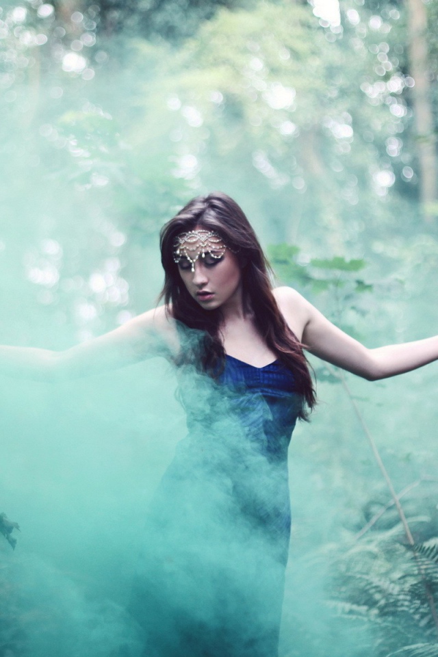 Девушка идет среди дыма по лесу